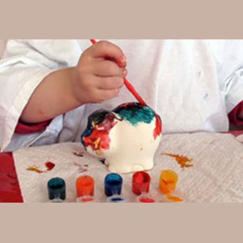 A child painting a plaster figure with bright paints
