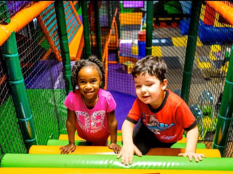 Two kids climbing through the Adventure Challenge play structure