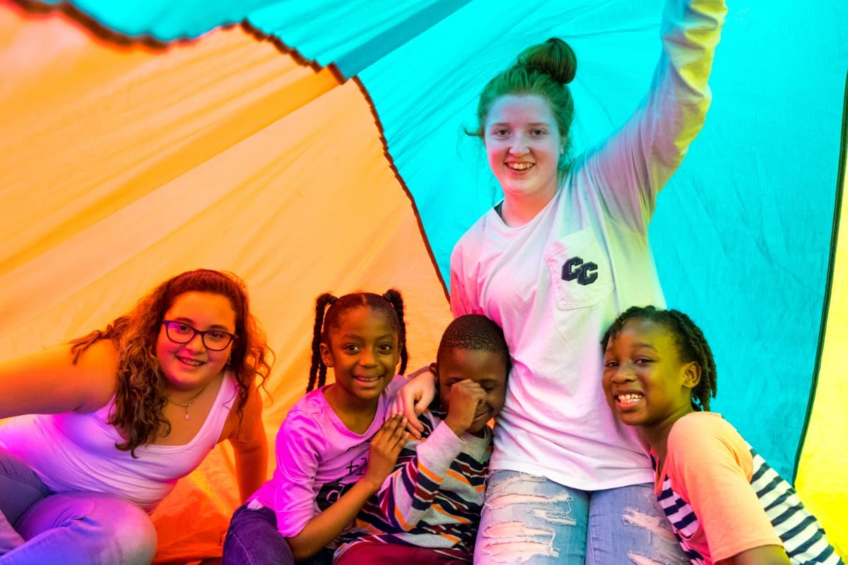 Girls laughing together in front of a bright painted wall at Kidsports