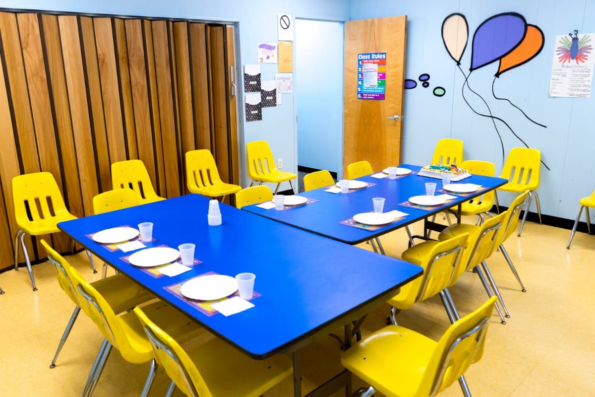 A private party room set with blue tables and yellow chairs