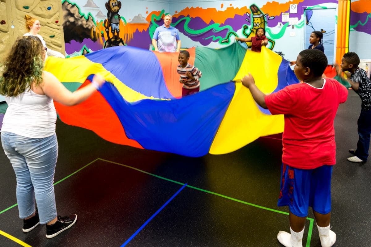 Kids playing parachute games during gym time at a Kidsports party