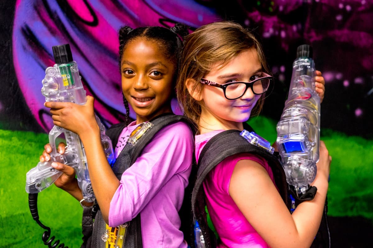 Two girls in laser tag vests holding their blasters